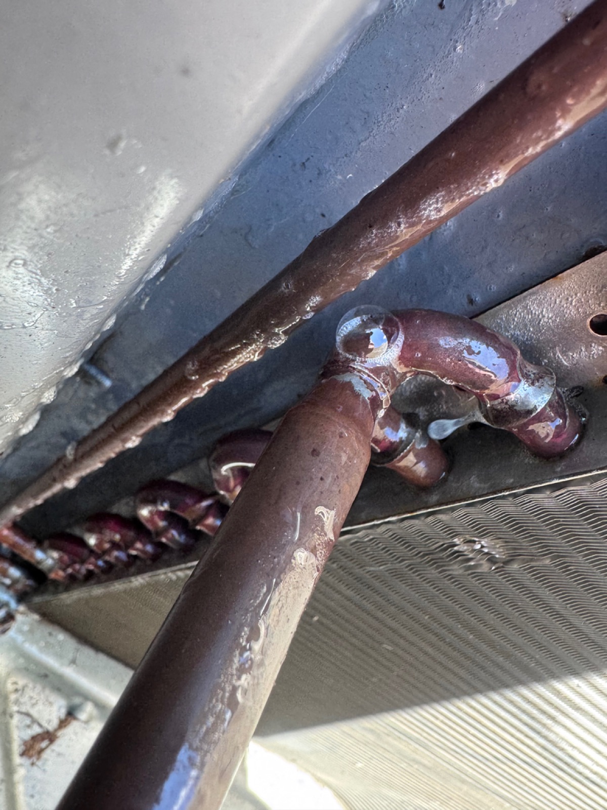 Close-up of brazed copper refrigerant line connections under an HVAC air handler by Wright Choice